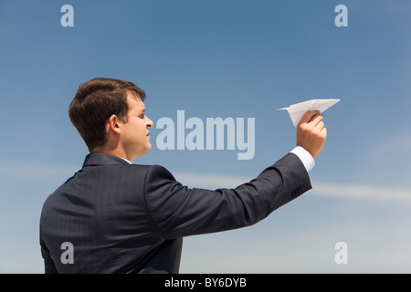 Photo of businessman holding paper aircraft in stretched hand before launching it Stock Photo
