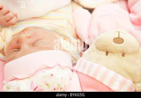 Cute little baby sleeping in pink pajama with teddy bear toy Stock Photo