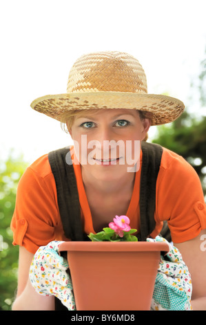 Happy young woman  gardening - potting Begonia flowers Stock Photo