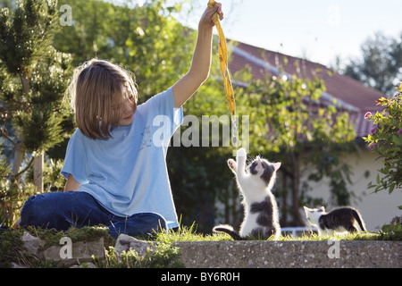 Girl playing with young domestic cat, kitten in the garden, Germany Stock Photo