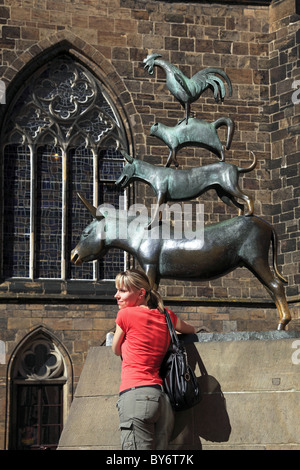 Young woman posing in front of the Bremen town musicans, Hanseatic City of Bremen, Germany, Europe Stock Photo