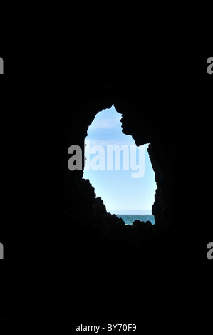 Sea view, looking through an elliptical silhouette cave entrance, of Bahia Cocotue waters, Pacific Coast, Chiloe Island, Chile Stock Photo