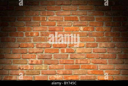 Weathered red brick wall texture lit dramatically from above Stock Photo