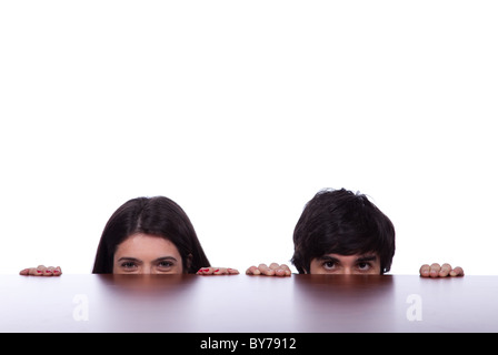 two business person hiding and peeking behind the office desk Stock Photo