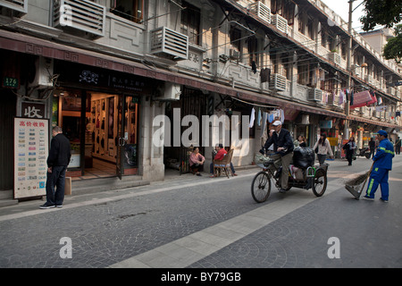 Man on bicycle passing by buildings, Duolan Road, Shanghai, China Stock Photo