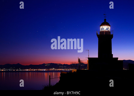 The lighthouse close to the Archaeological site of Heraion of Perachora with the town of Corinth in BG , Lourtraki, Greece Stock Photo