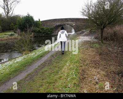 a woman walks along the towpath on the Liverpool to Manchester canal near Wigan