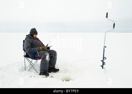 A fisherman is fishing in a hole on the ice of a large frozen lake on a  sunny day. The joy of winter fishing on Lake Baikal Stock Photo - Alamy
