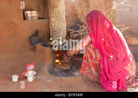 India, Rajasthan, Jodhpur, woman in traditional dress cooking roti (also known as chapati) on open fire Stock Photo