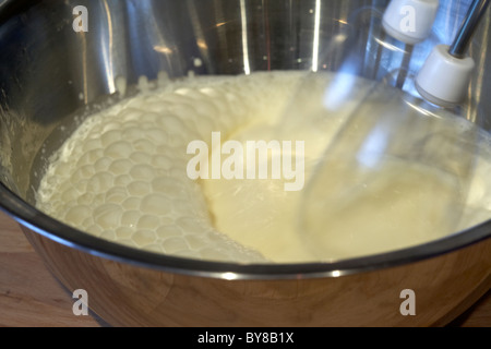 motion blur photo of electric whisk whisking fresh whipping cream in a metal mixing bowl Stock Photo