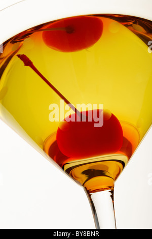 A closeup image of a yellow martini with a cherry, shown from below looking up.