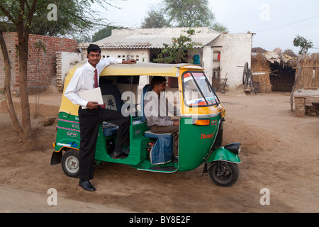 India, Uttar Pradesh, Agra, young businessman with laptop posing next to auto rickshaw on journey from home to work Stock Photo