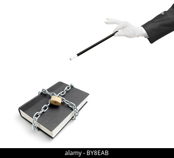 A magician holding a magic wand over a book with chain and padlock Stock Photo