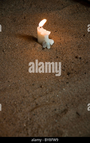 Lit candle in sand Stock Photo
