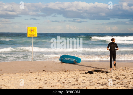 A surfer stands next to a lifesaving board at Bondi Beach in Sydney Australia Stock Photo