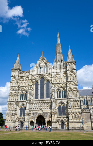 England Wiltshire Salisbury People on grass of Close in front of West Front main entrance of Gothic English Cathedral church Stock Photo
