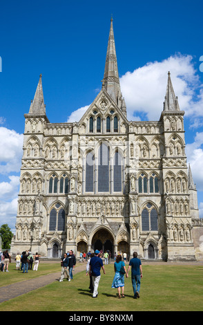 England Wiltshire Salisbury People on  grass of Close in front of West Front main entrance of Gothic Cathedral with spire Stock Photo
