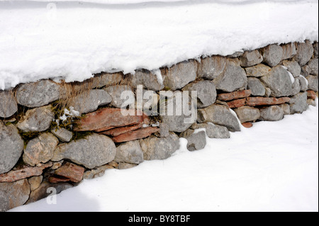 wall of stones covered with snow Stock Photo