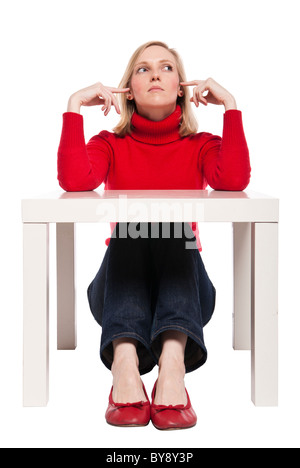 Young woman, office worker or student sitting at funny small desk. Studio photo, isolated. Stock Photo