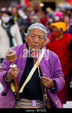 Old Tibetan women pilgrim wearing purple jacket with spinning prayer wheel in the Barkhor, Lhasa, Tibet. JMH4498 Stock Photo