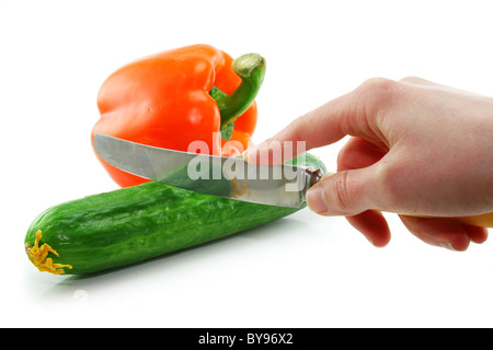 Woman's hand cuting green cucumber and orange paprika isolated Stock Photo