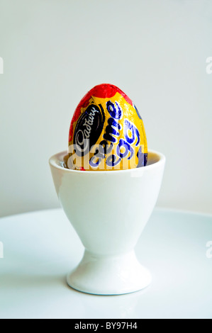 A Cadbury Creme Egg in a white egg cup on a white plate. Stock Photo