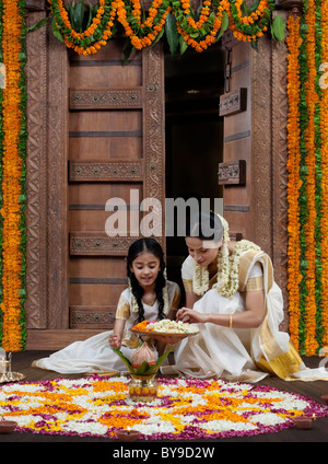 South Indian woman helping her daughter with a rangoli Stock Photo