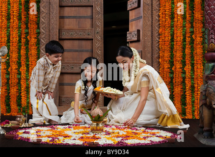 South Indian woman making a flower rangoli with son and daughter Stock Photo