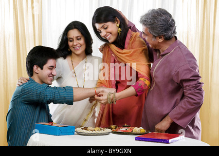 Girl tying a rakhi on her brothers hand Stock Photo