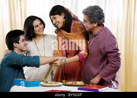 Girl tying a rakhi on her brothers hand Stock Photo