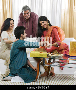 Girl tying a rakhi on her brothers hand Stock Photo