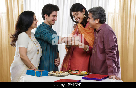 Girl tying a rakhi on her brothers hand Stock Photo