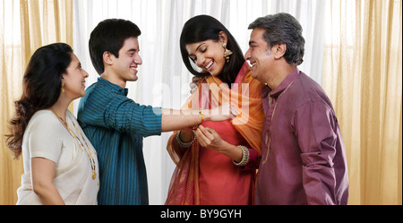 Girl tying a rakhi on her brothers hand Stock Photo