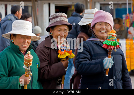Three smiling old Tibetan women pilgrims wearing hats and spinning colourful prayer wheels in the Barkhor Lhasa Tibet. JMH4646 Stock Photo