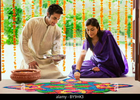 Couple making a rangoli Stock Photo - Alamy