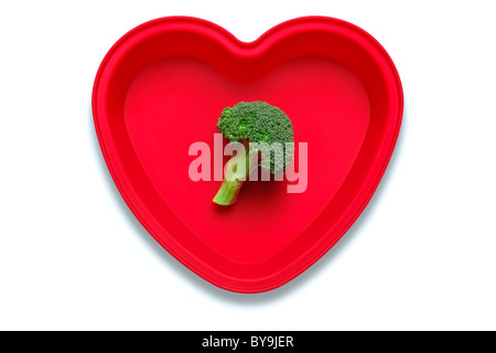 Conceptual photo of broccoli in a heart shaped dish to represent a love of the vegetable, isolated on a white background Stock Photo