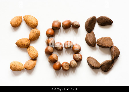 Almonds, Hazelnuts and Brazil Nuts laid out against a white background in the numbers 3, 6 and 5 Stock Photo