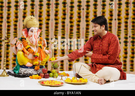 Man offering flowers to Lord Ganesh Stock Photo