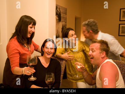 Group with wine glasses gossiping over dinner table Stock Photo