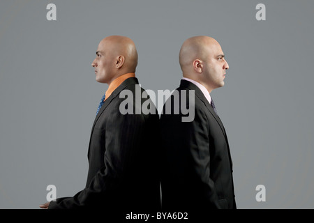 Two bald businessmen standing back to back Stock Photo