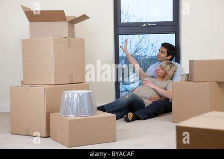 Couple sat amongst boxes in apartment Stock Photo