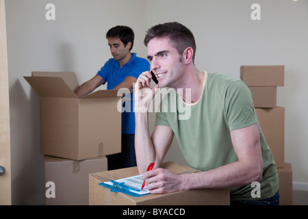 Two men unpacking boxes in apartment Stock Photo