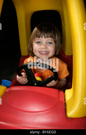 Young girl (2-3) at the steering wheel of a toy car . MODEL RELEASED Stock Photo