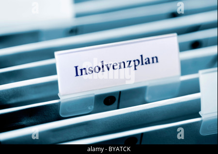 Rider on a hanging folder labeled Insolvenzplan or bankruptcy plan Stock Photo