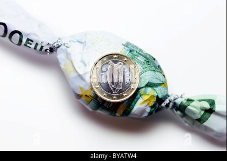 Irish one euro coin on a hundred euro banknote wrapped like a bonbon, symbolic image for EU funding for Ireland Stock Photo