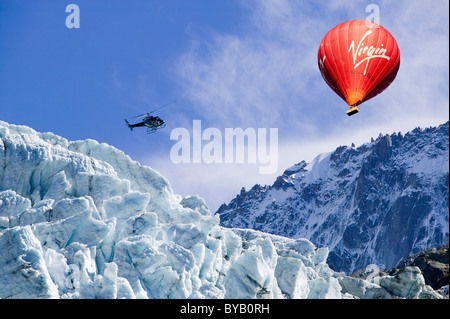 A hot air balloon and helicopter over the Argentiere Glacier like most glaciers it is retreating rapidly due to climate change. Stock Photo