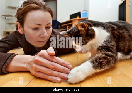 Young woman playing with old male cat on the floor Stock Photo