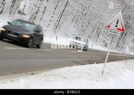 Traffic on a snow-covered country road, road sign 'Strassenschaeden', German for 'road damage', Baden-Wuerttemberg Stock Photo