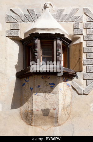 Historic bay window of a typical Engadine house with wood carvings and painted flowers in the historic town of Ardez Stock Photo