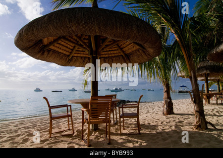 Table and chairs under sunshade on the beach of Le Paradis Hotel, Mauritius, Africa Stock Photo